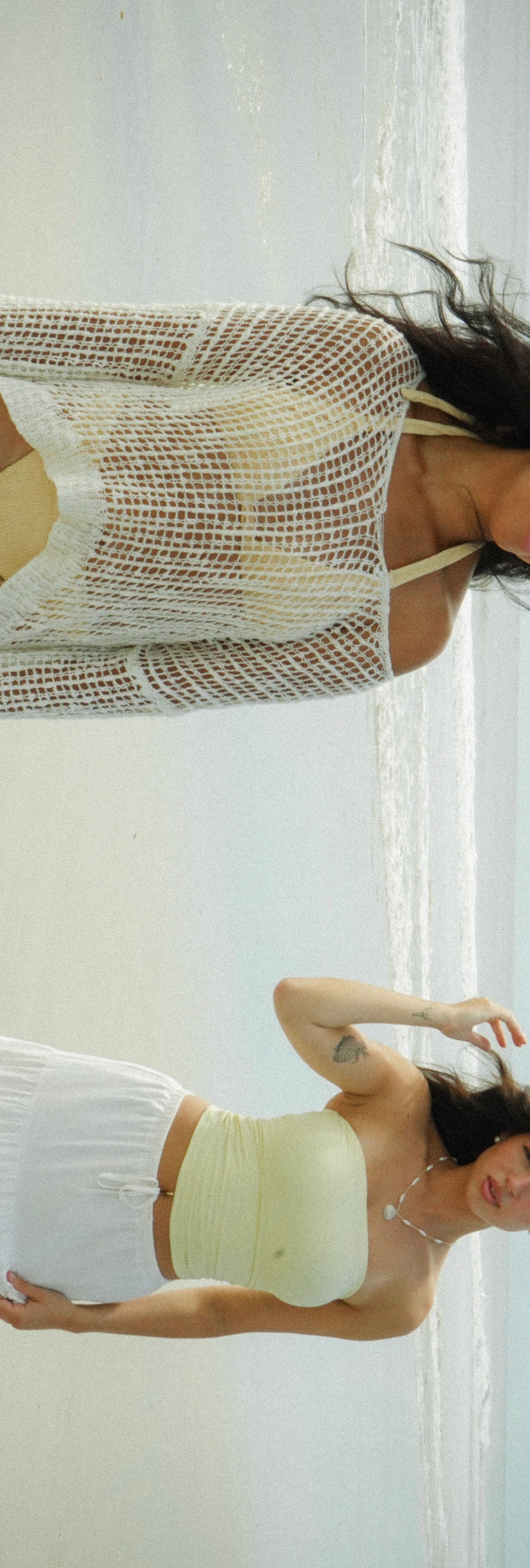 Person wearing cream mesh crop top and white shorts posing against white wall, shown from side profile