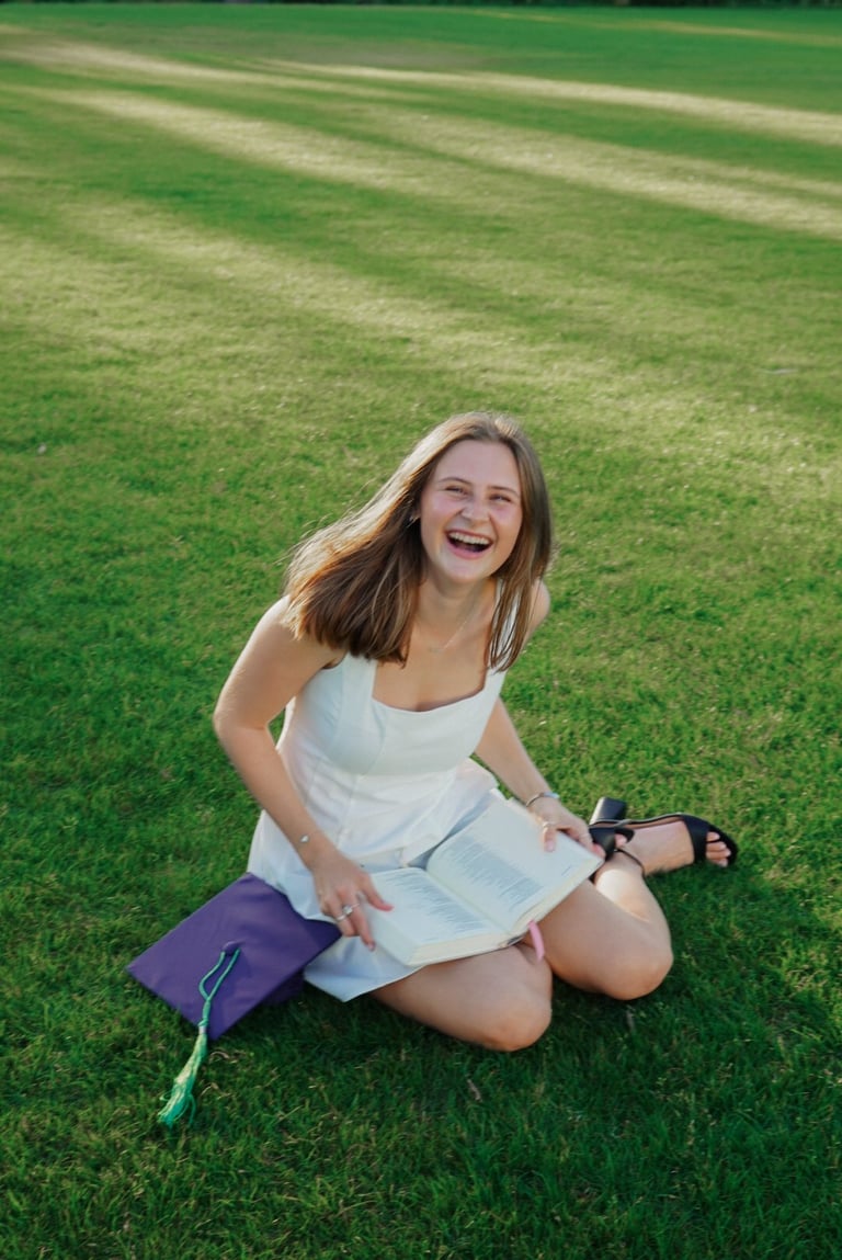 Smiling woman in white tank top kneeling on grass with purple bag, wearing sporty gloves