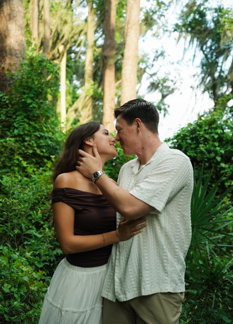 Couple kissing in a lush green garden surrounded by ivy-covered trees and foliage