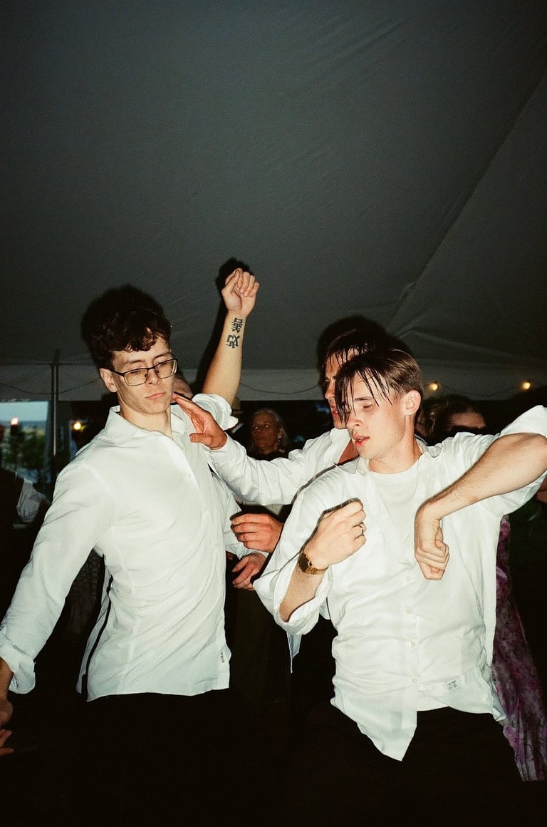Two people in white shirts dancing together at an indoor event under a tent with other guests in the background