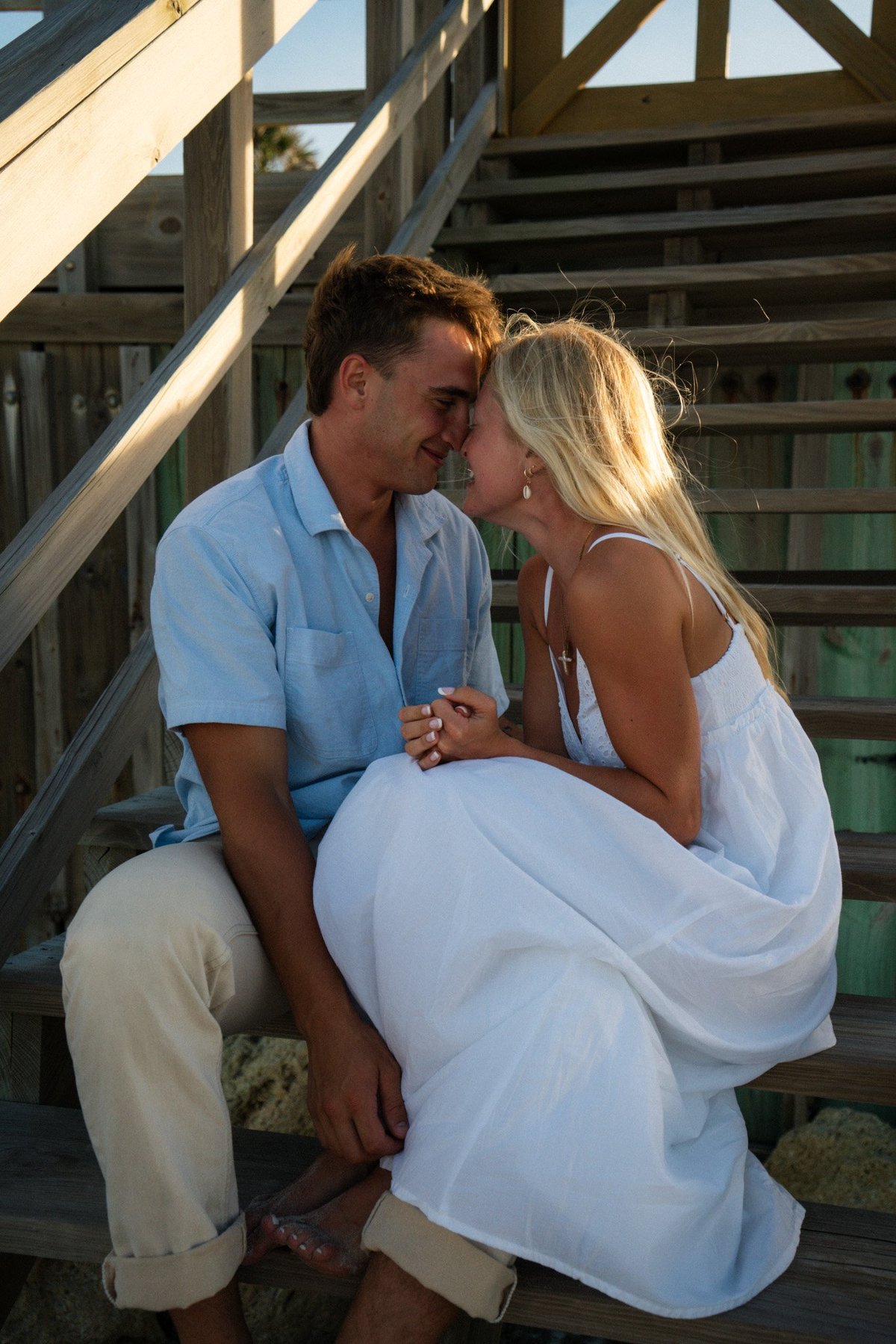 A couple embracing on wooden deck stairs on a sunny day